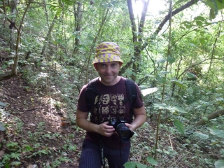 Camoflage hat, camoflage T-shirt, Tim moves stealthily through the forest