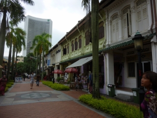 A row of restored colonial shophouses, watched over by the more typical modern steel and glass of Singapore