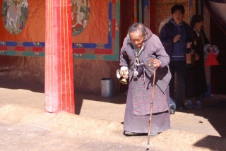 An elderly pilgrim on her devotional rounds at Drepung monastery
