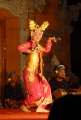 A legong dancer steps across the stage, her gaze fixed